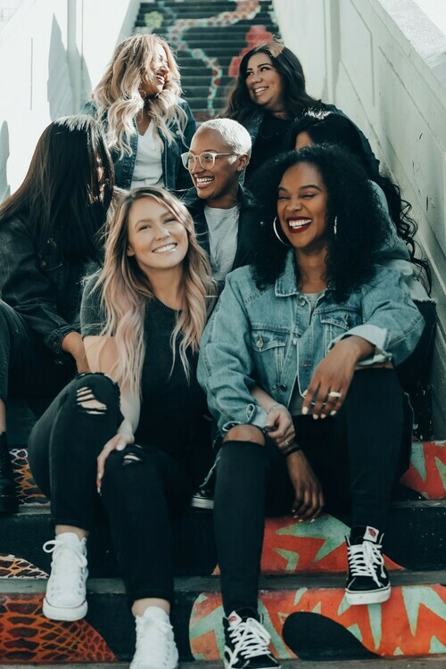 A group of students sit on a narrow stairwell and smile together.